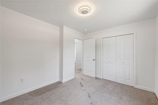 unfurnished bedroom featuring light carpet and a closet