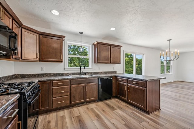 kitchen with kitchen peninsula, light wood-type flooring, decorative light fixtures, and black appliances