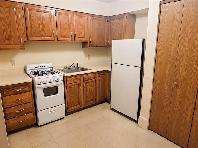 kitchen with white appliances, a sink, light countertops, and brown cabinetry