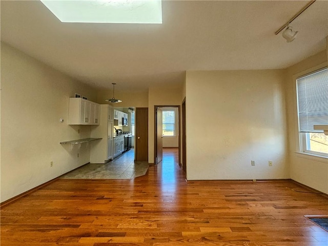 unfurnished living room with wood finished floors, plenty of natural light, and baseboards