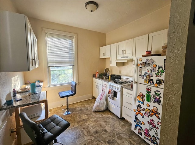 kitchen featuring white appliances, a sink, under cabinet range hood, baseboards, and white cabinets