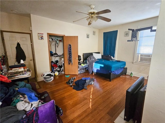 bedroom featuring wood finished floors, cooling unit, and a ceiling fan