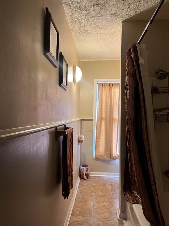 bathroom with shower / bath combination with curtain and a textured ceiling