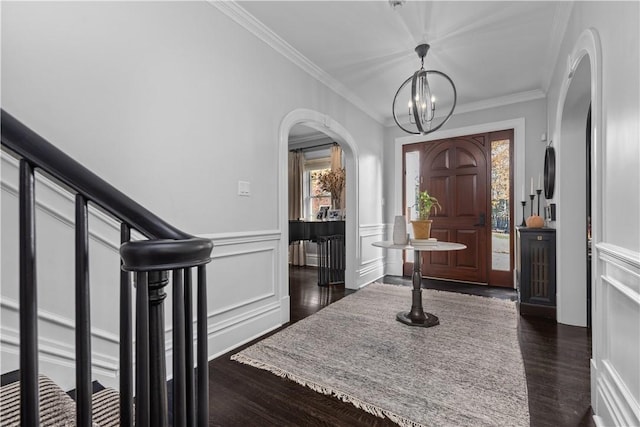 entryway featuring dark hardwood / wood-style floors, crown molding, and an inviting chandelier