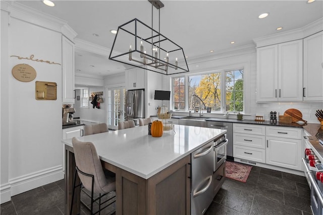 kitchen featuring white cabinetry, sink, stainless steel appliances, tasteful backsplash, and a kitchen island