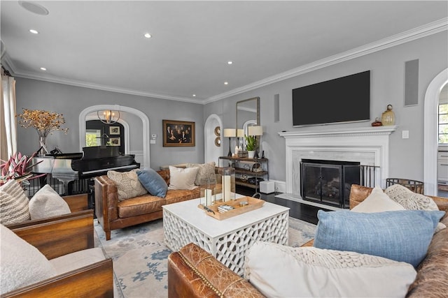 living room featuring a high end fireplace, a chandelier, light hardwood / wood-style flooring, and crown molding