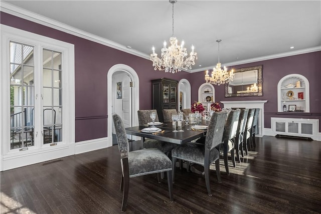 dining space with built in features, ornamental molding, dark hardwood / wood-style floors, and an inviting chandelier