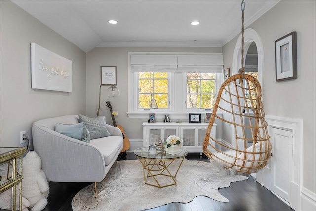 living area with wood-type flooring, ornamental molding, and vaulted ceiling