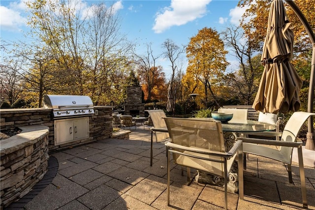 view of patio featuring an outdoor stone fireplace, area for grilling, and exterior kitchen