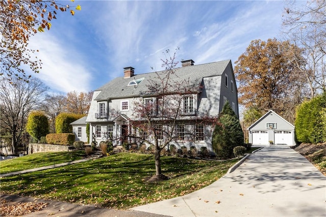 view of front of property with a garage, an outbuilding, and a front lawn