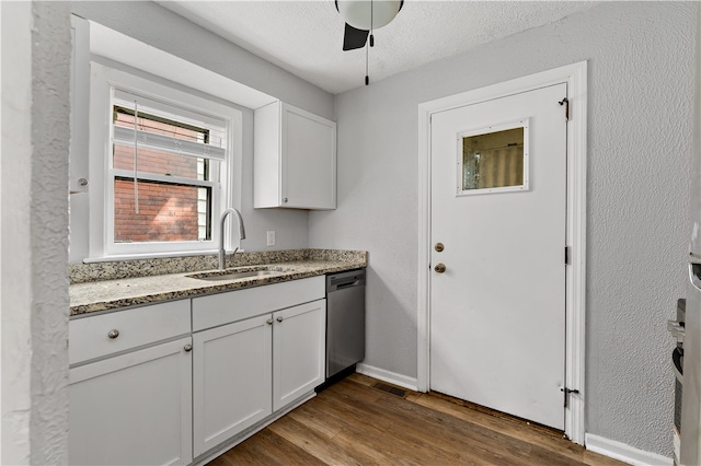 kitchen featuring dark wood-type flooring, white cabinets, dishwasher, sink, and dark stone countertops