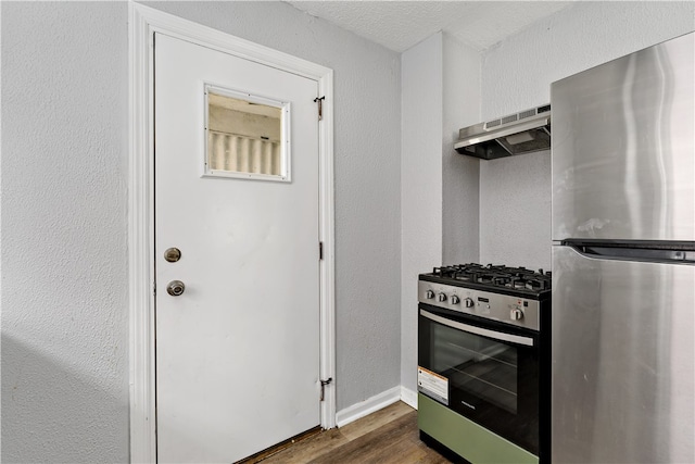 kitchen featuring stainless steel appliances, a textured ceiling, extractor fan, and dark wood-type flooring