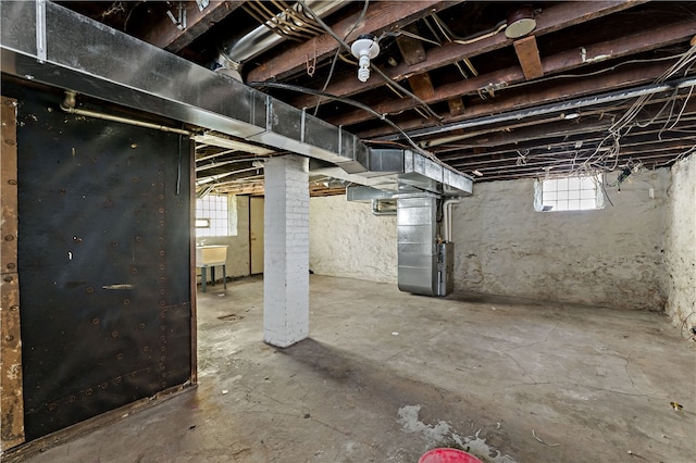 basement featuring plenty of natural light, sink, and heating unit