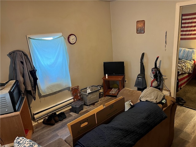 bedroom with dark hardwood / wood-style floors and baseboard heating