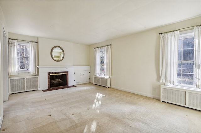 unfurnished living room with light colored carpet, radiator heating unit, and a fireplace