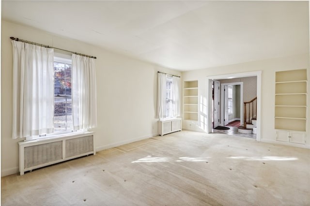 carpeted empty room featuring radiator heating unit and built in features