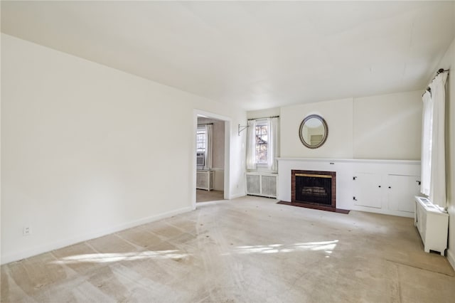 unfurnished living room with radiator heating unit and light colored carpet