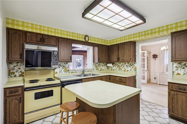 kitchen featuring dishwashing machine, dark brown cabinets, sink, electric range, and a breakfast bar area