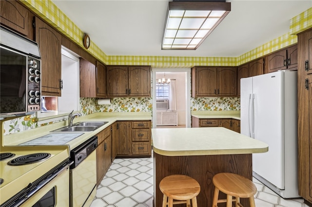 kitchen featuring a kitchen bar, white appliances, cooling unit, sink, and a chandelier