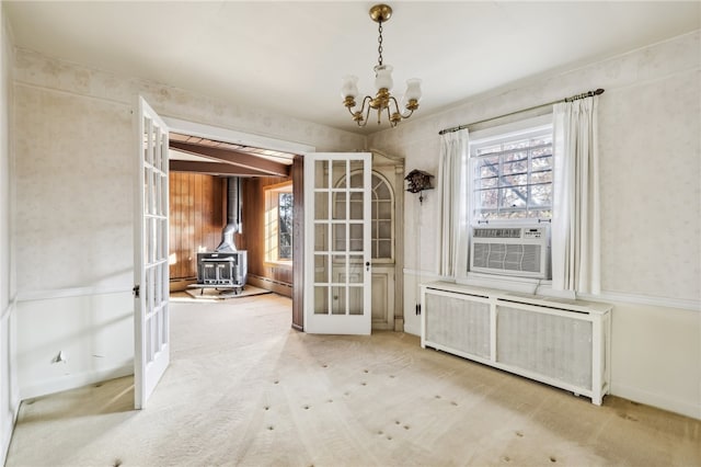 unfurnished dining area featuring french doors, cooling unit, a chandelier, radiator heating unit, and a wood stove