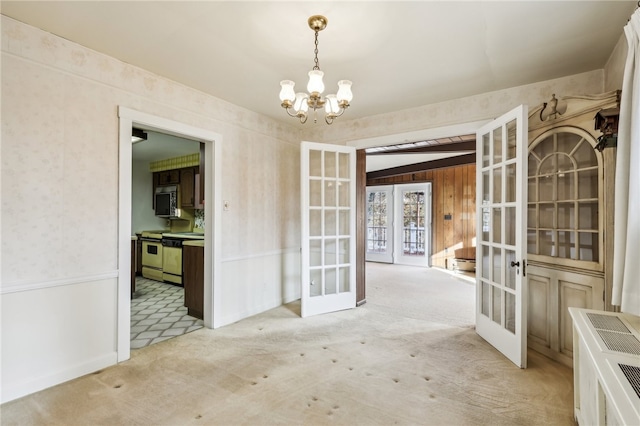 unfurnished dining area with a notable chandelier, light carpet, and french doors