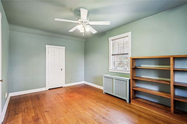 unfurnished room featuring radiator heating unit, light hardwood / wood-style flooring, and ceiling fan