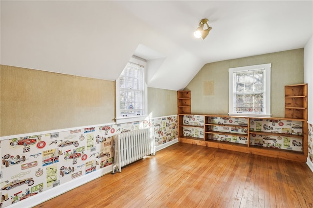 additional living space with hardwood / wood-style flooring, radiator, and vaulted ceiling