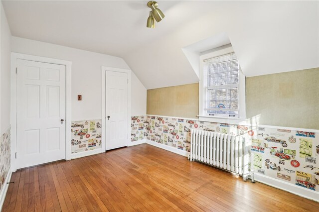 bonus room with radiator heating unit, hardwood / wood-style floors, and vaulted ceiling