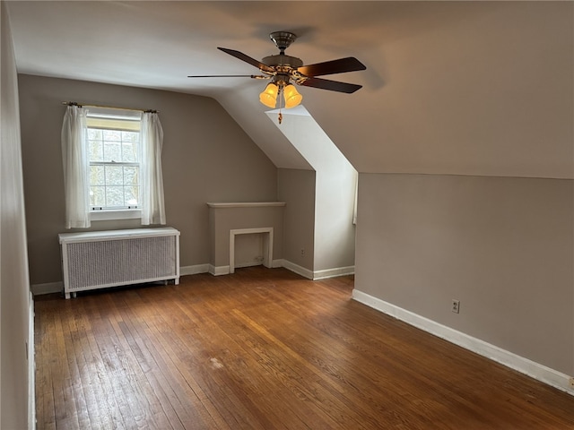 additional living space featuring hardwood / wood-style flooring, vaulted ceiling, radiator, and ceiling fan