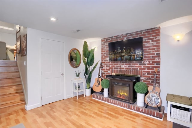 living room with wood-type flooring and a brick fireplace