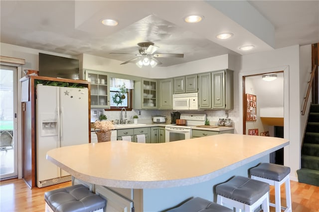 kitchen featuring ceiling fan, sink, white appliances, decorative backsplash, and light wood-type flooring