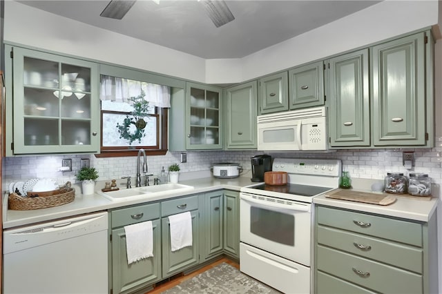 kitchen featuring backsplash, white appliances, sink, and green cabinetry