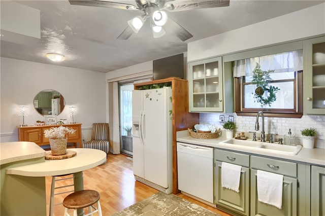 kitchen featuring sink, backsplash, light hardwood / wood-style floors, white appliances, and green cabinetry