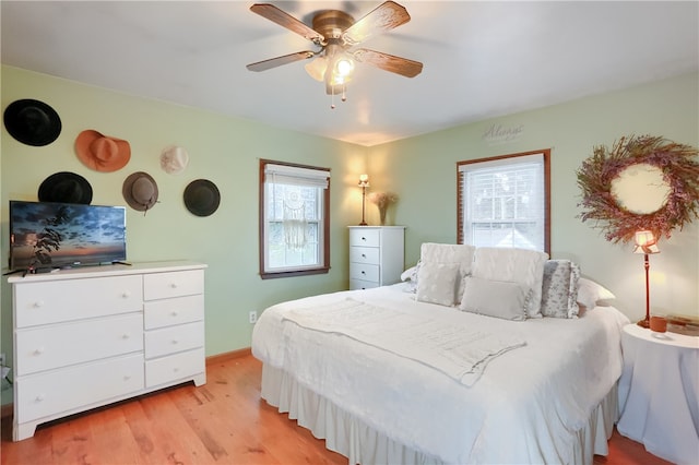 bedroom with ceiling fan, light hardwood / wood-style floors, and multiple windows