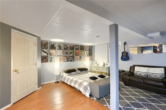 bedroom with wood-type flooring and a drop ceiling