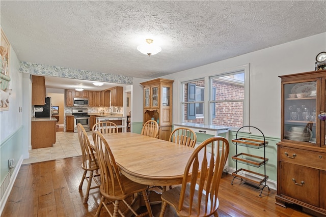 dining room featuring light hardwood / wood-style flooring and a textured ceiling