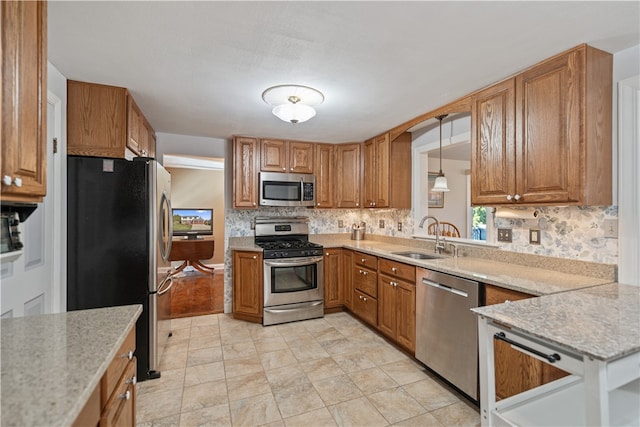 kitchen featuring backsplash, light stone counters, stainless steel appliances, sink, and hanging light fixtures