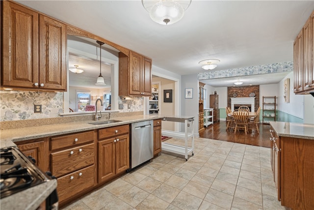 kitchen with pendant lighting, backsplash, sink, stainless steel dishwasher, and a fireplace