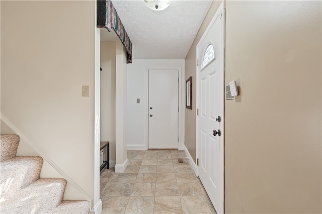 doorway to outside with a textured ceiling