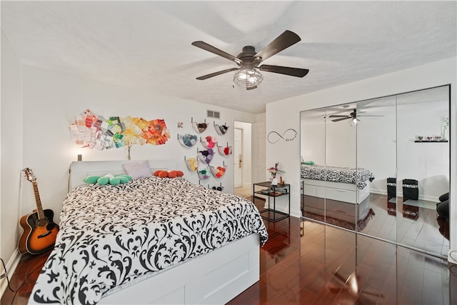 bedroom featuring dark hardwood / wood-style flooring, ceiling fan, a closet, and a textured ceiling