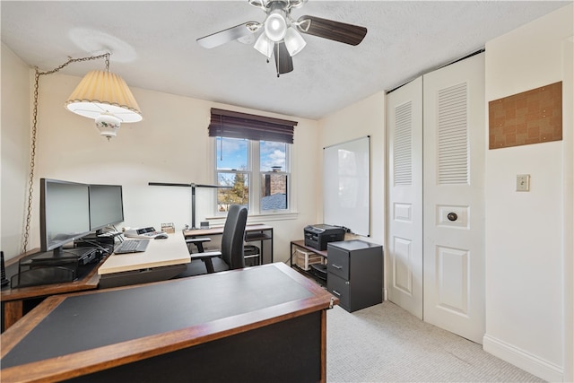 carpeted home office with ceiling fan and a textured ceiling