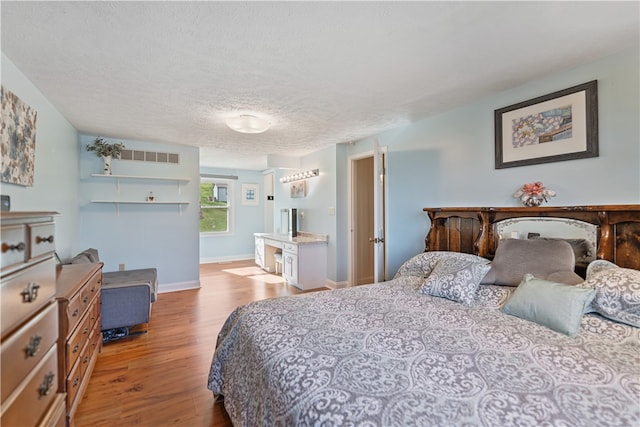 bedroom with light hardwood / wood-style floors and a textured ceiling