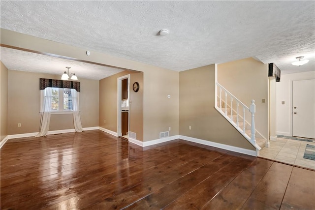 unfurnished room with dark hardwood / wood-style flooring, a chandelier, and a textured ceiling