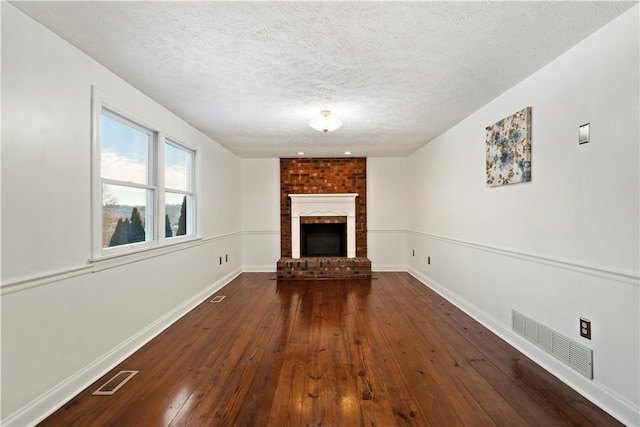 unfurnished living room with dark wood-type flooring, a textured ceiling, and a fireplace