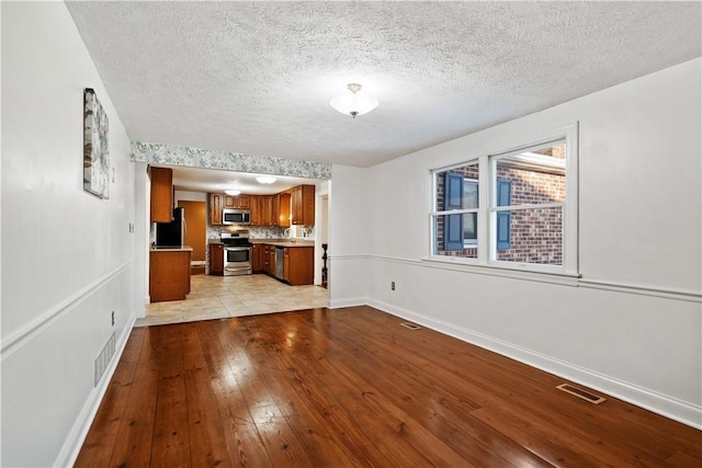 unfurnished living room featuring light hardwood / wood-style flooring and a textured ceiling