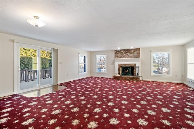 unfurnished living room with carpet floors, a wealth of natural light, a textured ceiling, and a fireplace