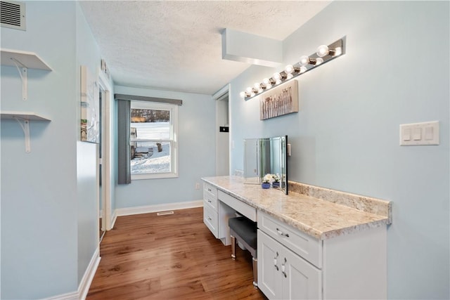 bathroom with hardwood / wood-style flooring, vanity, and a textured ceiling