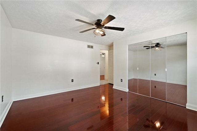 unfurnished bedroom featuring dark hardwood / wood-style flooring, ceiling fan, a closet, and a textured ceiling