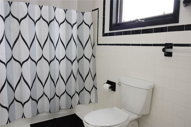 bathroom featuring toilet and tile walls