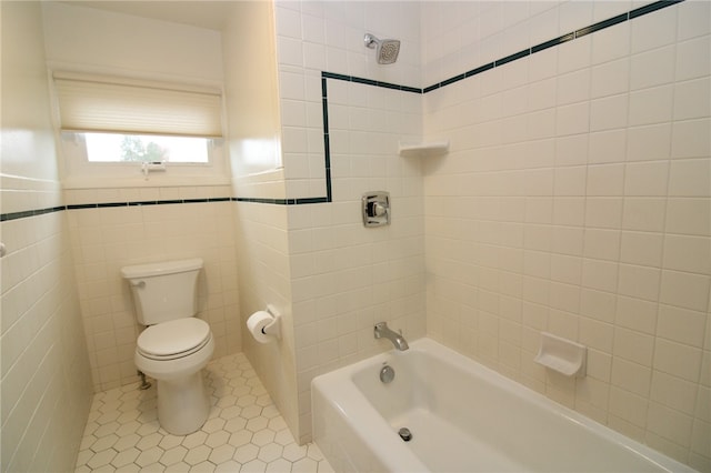 bathroom with tile walls, tile patterned flooring, toilet, and tiled shower / bath